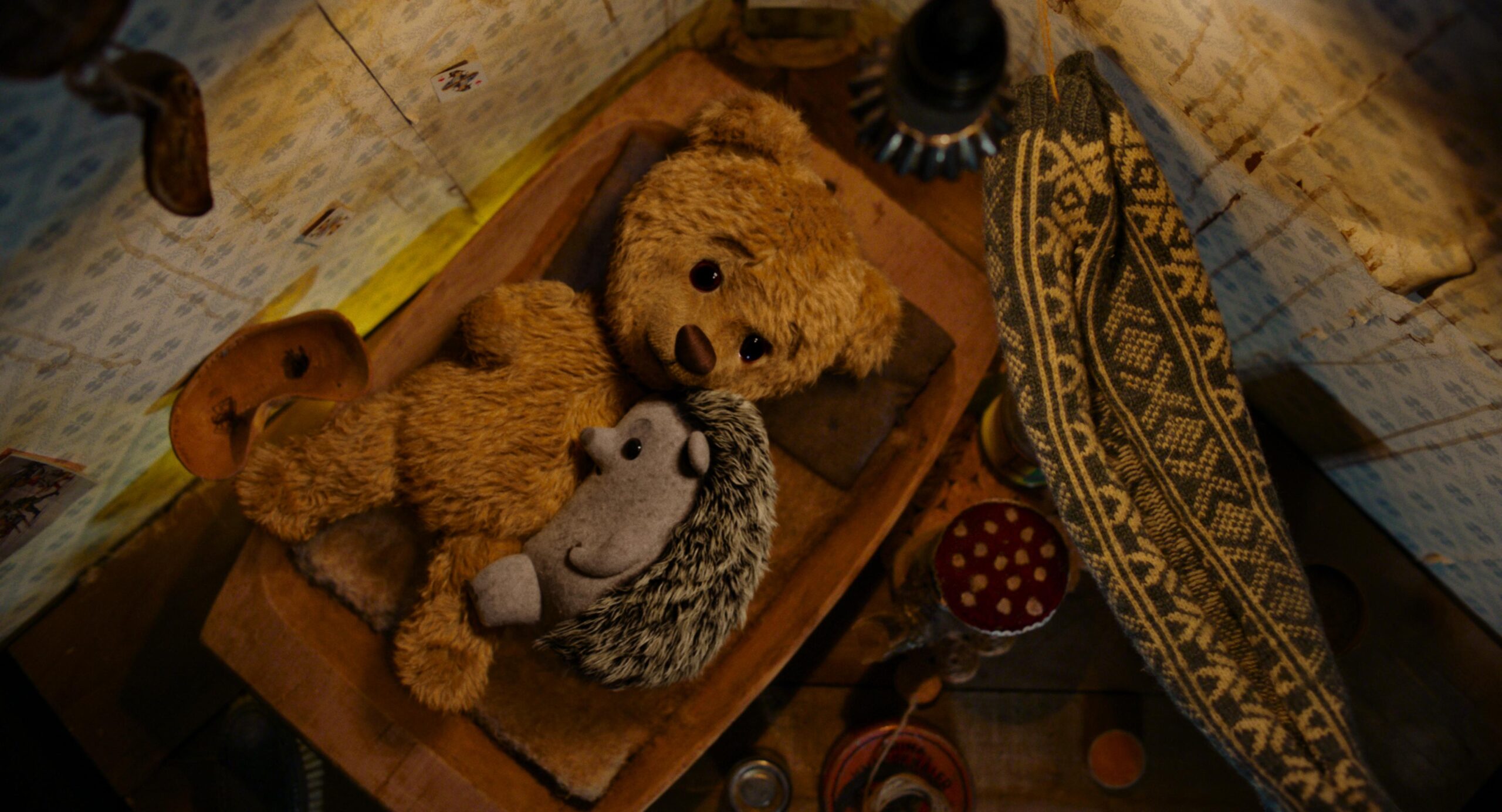 Teddybeer en knuffel egel liggend op een bed