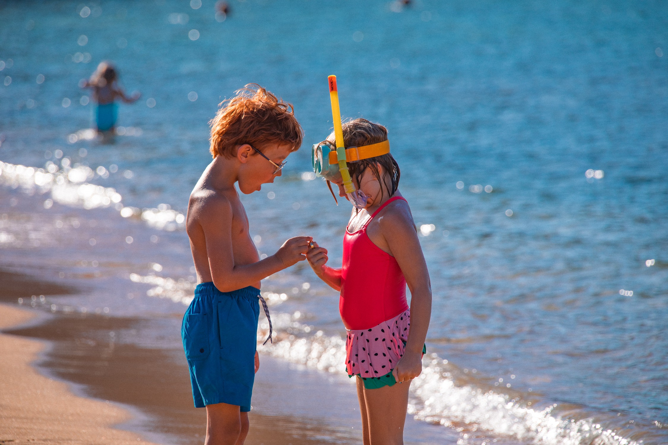 Jongen en meisje in badkleding kijken verbaasd naar een gevonden een ring op het strand