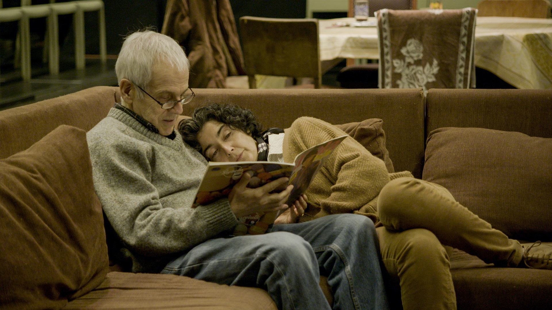 Een ouder echtbaar ligt op de bank en leest samen een boek