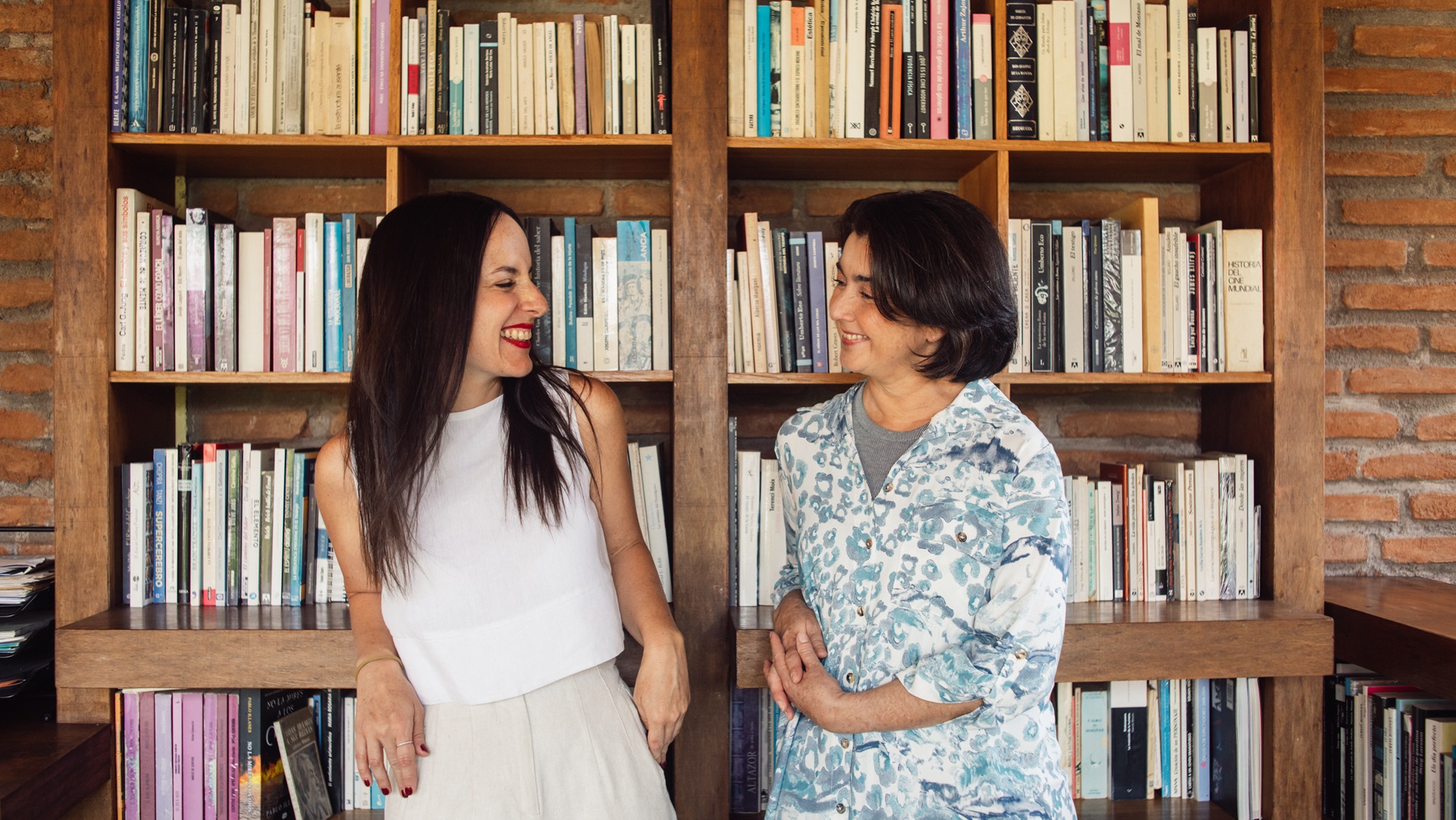 Moeder en dochter lachen naar elkaar voor een boekenkast