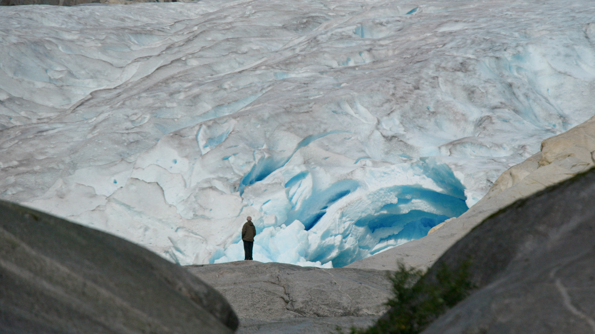 Een persoon staat voor een enorme gletsjer