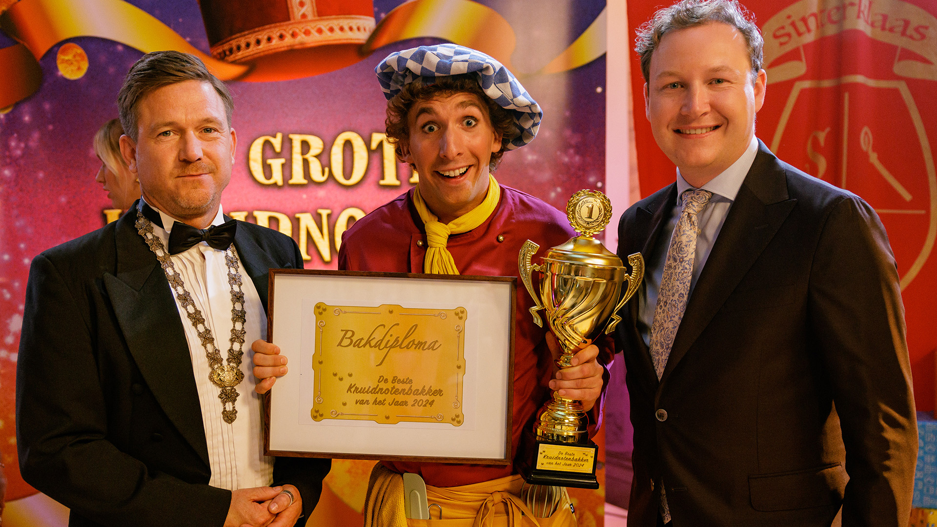 Een bakker staat op de foto als winnaar van een bakwedstrijd met de jury en burgemeester