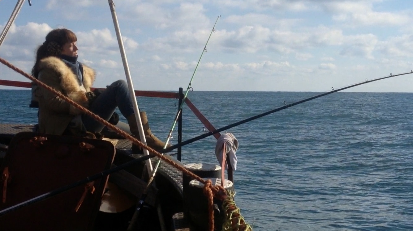 Warnow_still (3) Vrouw op schip kijkt in de verte met een hengel naast zich